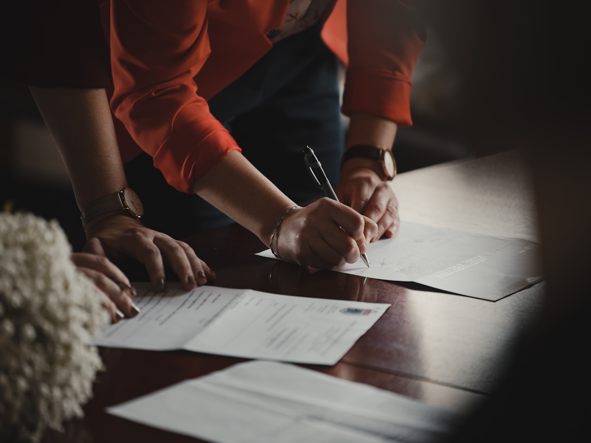 Two people reviewing and signing printed documents at a desk
